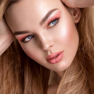 Model wearing a full face of makeup showing how to apply blusher